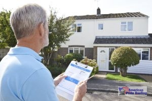 roofer holds inspection checklist in front of house