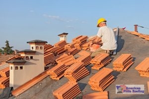 roofer sits on roof with tiles watiging to be installed